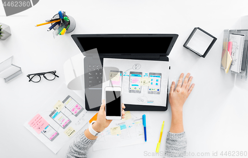 Image of web designer with smartphone and laptop at office