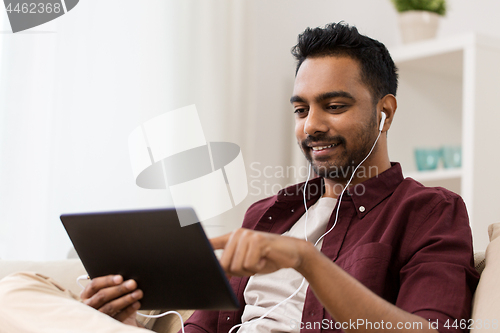 Image of man in earphones with tablet pc listening to music