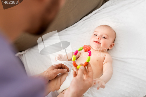 Image of close up of father giving rattle to baby girl