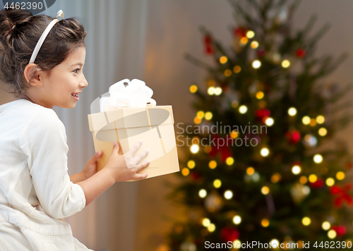 Image of happy little girl with christmas gift at home