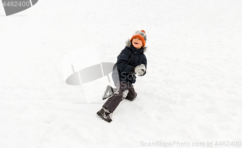 Image of happy little boy playing with snow in winter