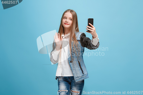 Image of The happy teen girl standing and smiling against pink background.