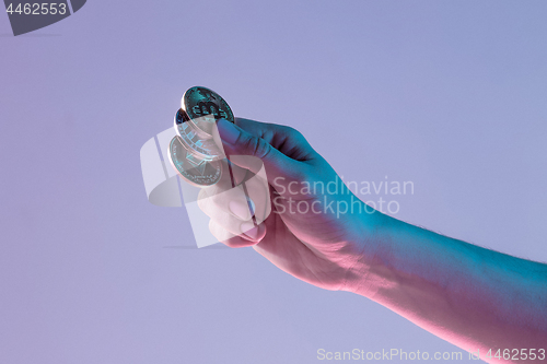 Image of Male hand with golden bitcoin on blue background