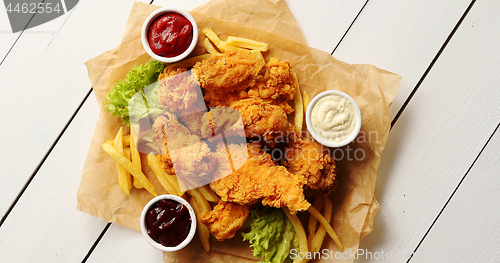 Image of Sauces and lettuce near French fries and chicken wings