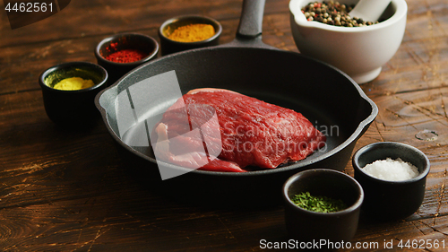 Image of Bowls with spices near uncooked meat