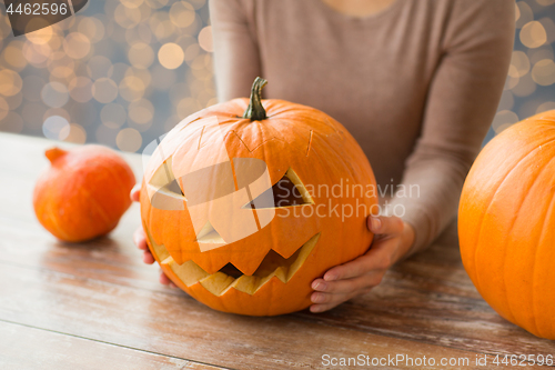 Image of close up of woman with halloween pumpkin at home