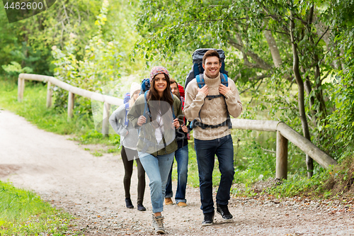 Image of happy friends or travelers hiking with backpacks