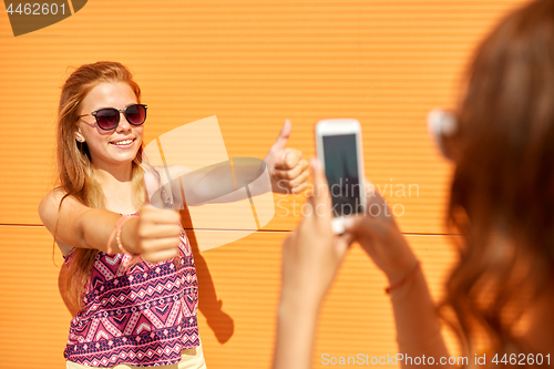 Image of teenage girl photographing friend by smartphone