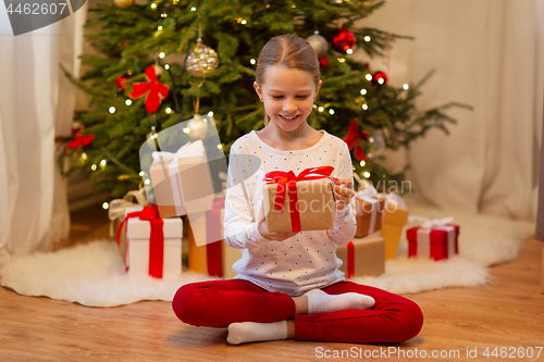 Image of smiling girl with christmas gift at home