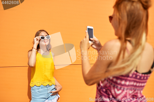 Image of teenage girl photographing friend by smartphone