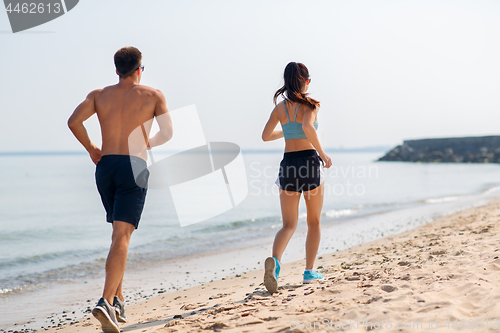 Image of couple in sports clothes running along on beach