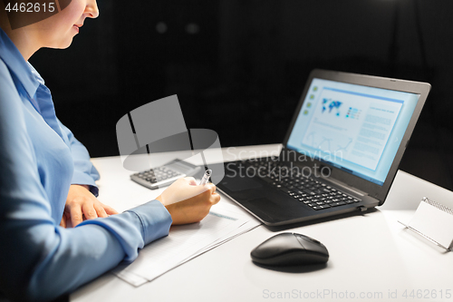 Image of businesswoman with papers working at night office