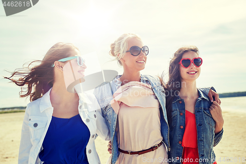 Image of group of smiling women in sunglasses on beach