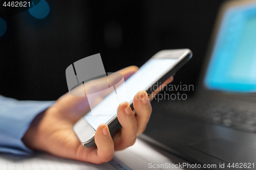 Image of close up of hand with smartphone at night office