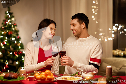 Image of happy couple drinking red wine at christmas dinner