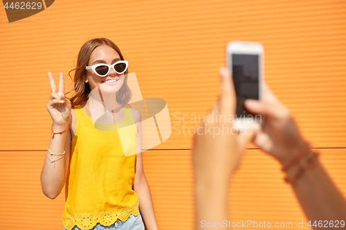 Image of teenage girl photographing friend by smartphone