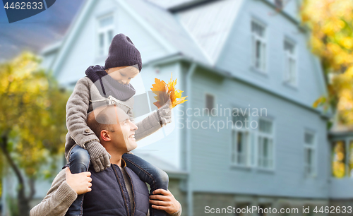 Image of father and son with autumn maple leaves over house