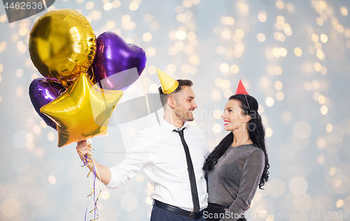 Image of happy couple in party hats with balloons