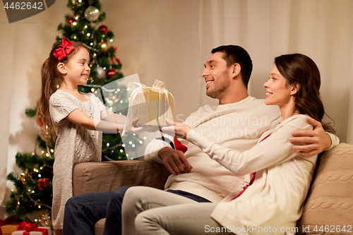 Image of happy family with christmas present at home
