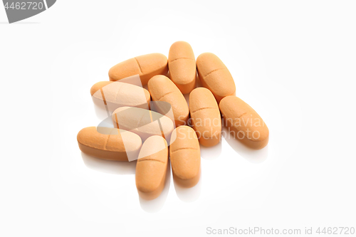 Image of Heap of orange pills on white background