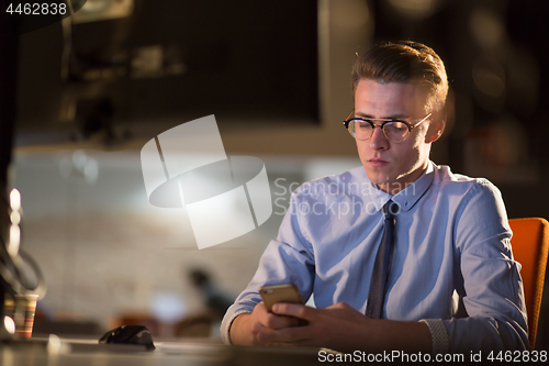 Image of man using mobile phone in dark office