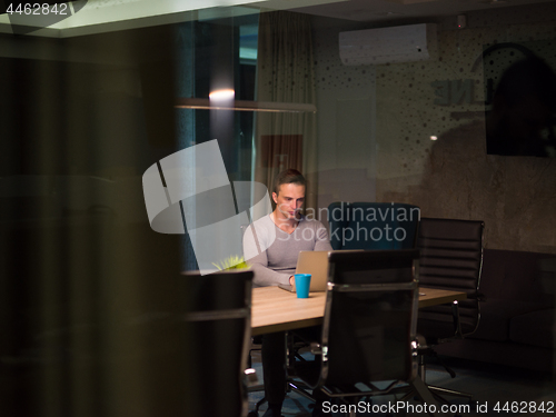 Image of man working on laptop in dark office