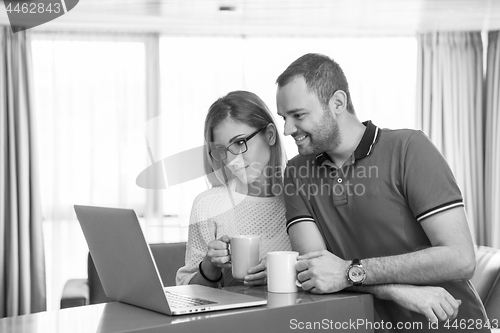 Image of couple drinking coffee and using laptop at home