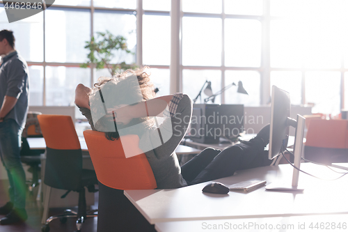 Image of businessman sitting with legs on desk