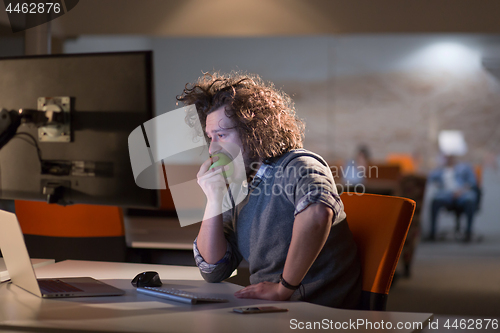 Image of man eating apple in his office