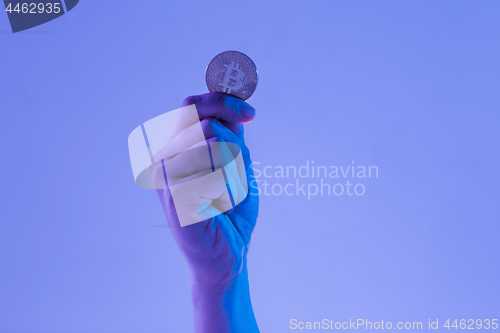 Image of Male hand with golden bitcoin on blue background