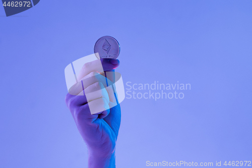 Image of Male hand with golden Ethereum on blue background