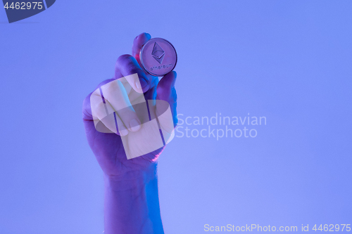 Image of Male hand with golden Ethereum on blue background