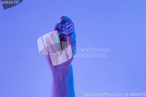 Image of Male hand with golden Litecoin on blue background