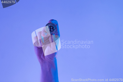 Image of Male hand with golden bitcoin on blue background
