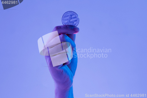 Image of Male hand with golden Litecoin on blue background