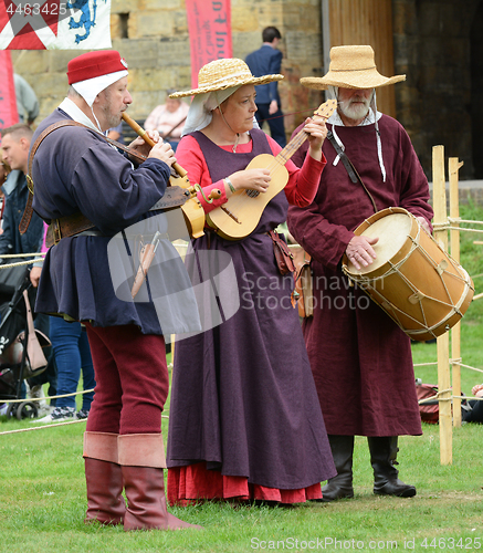 Image of Three musicians perform at a fair in medieval costume