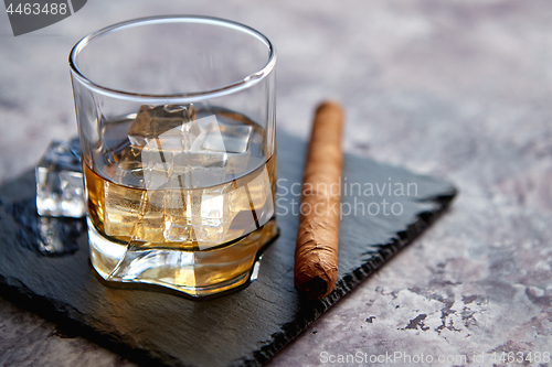 Image of Glass of whiskey with ice cubes and cigar