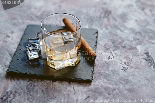 Image of Glass of whiskey with ice cubes and cigar