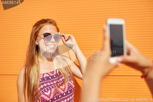 Image of teenage girl photographing friend by smartphone