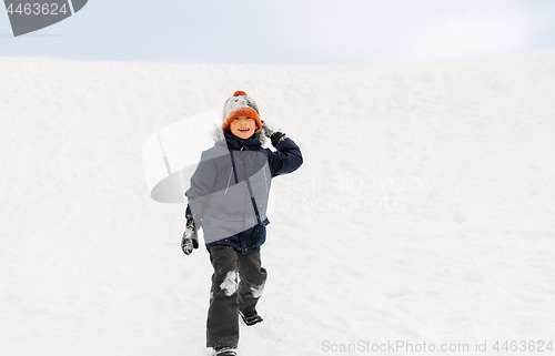 Image of happy boy playing and throwing snowball in winter