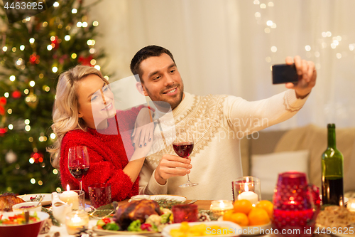 Image of happy couple taking selfie at christmas dinner