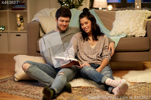 Image of happy couple reading book at home