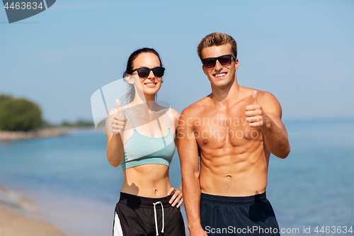 Image of couple of athletes showing thumbs up on beach