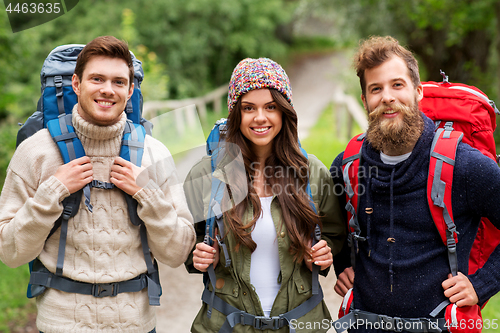 Image of happy friends or travelers with backpacks hiking
