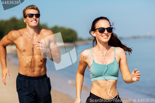 Image of couple with earphones running along on beach