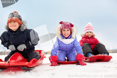 Image of happy little kids sliding down on sleds in winter