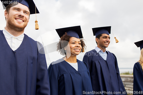 Image of happy students or bachelors in mortar boards