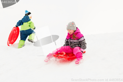 Image of happy kids sliding on sleds down hill in winter