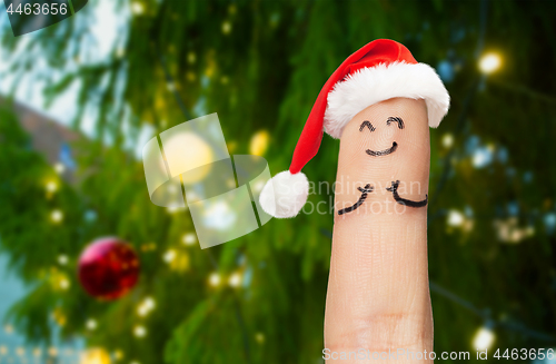 Image of one finger in santa hat over christmas tree