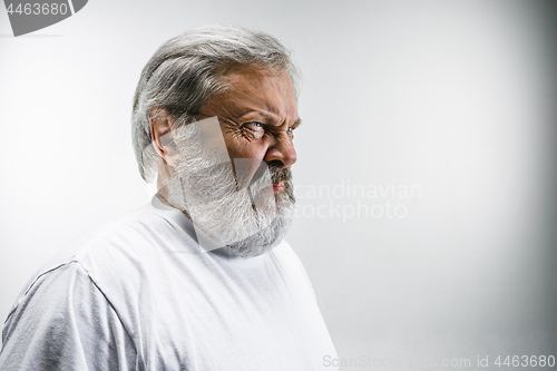 Image of Senior man with disgusted expression repulsing something on white